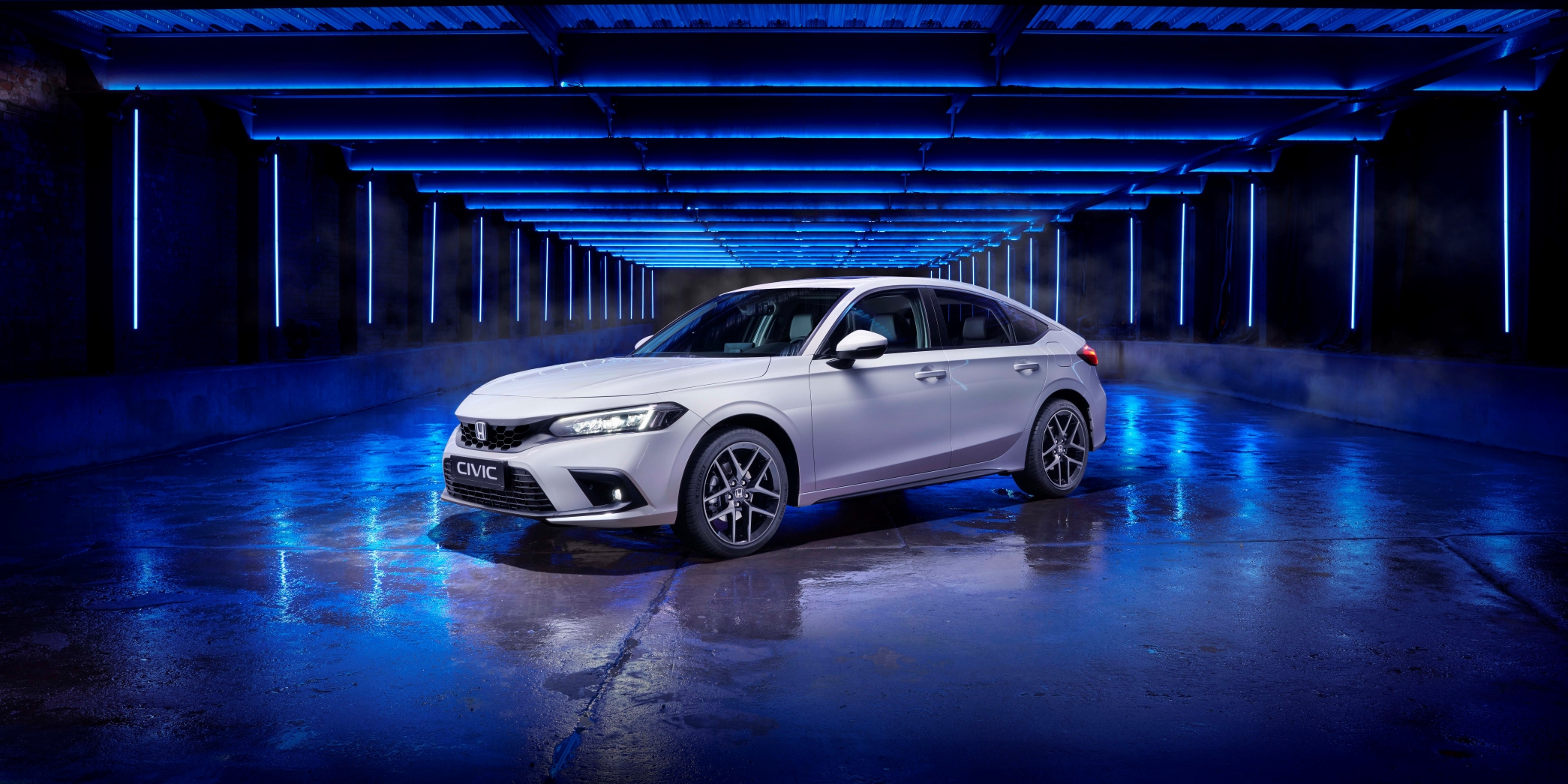 3/4-Frontansicht des neuen 2022er Honda Civic in Weiß, aufgenommen in einem blau beleuchteten Studio